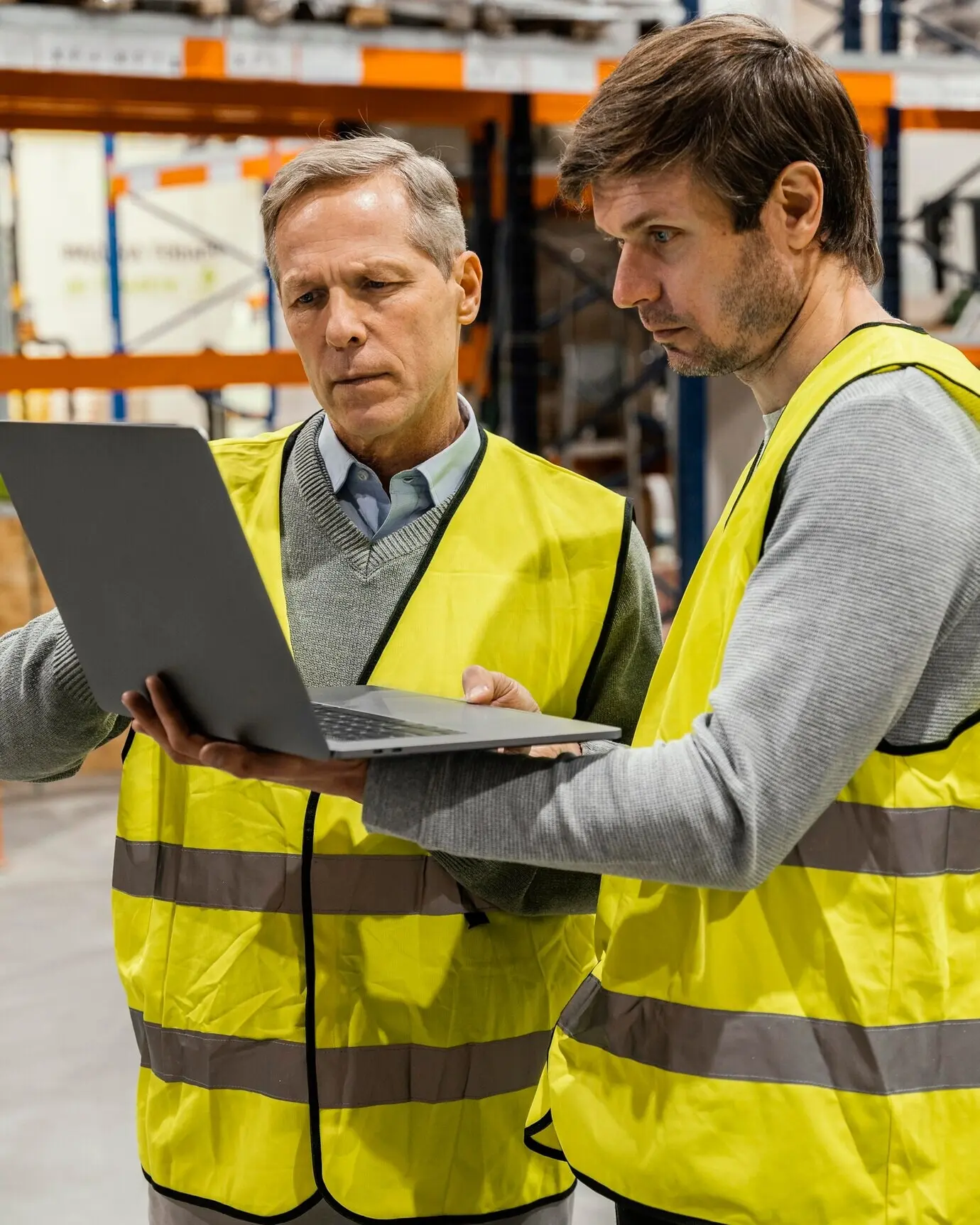 Мужчины на складе работают за ноутбуком.